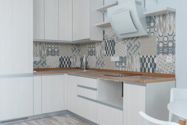 kitchen Interior of contemporary kitchen with white cabinets and wooden counter near ornamental tile on wall and modern appliances in apartment