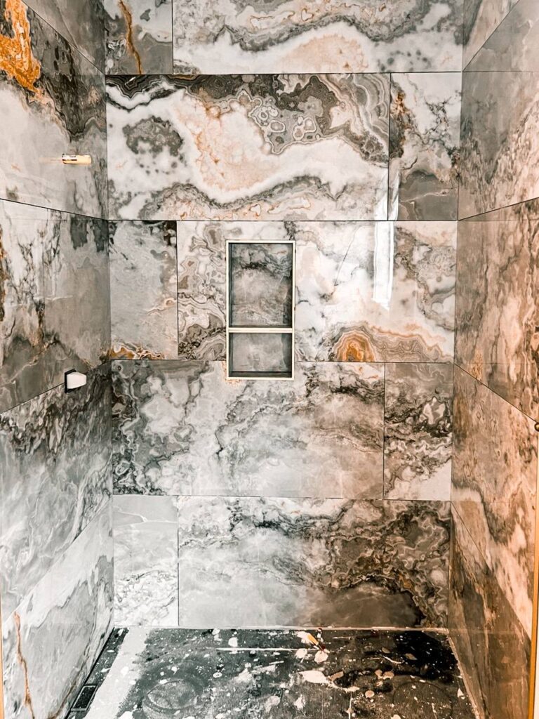 Large-format marble-look shower walls with niche