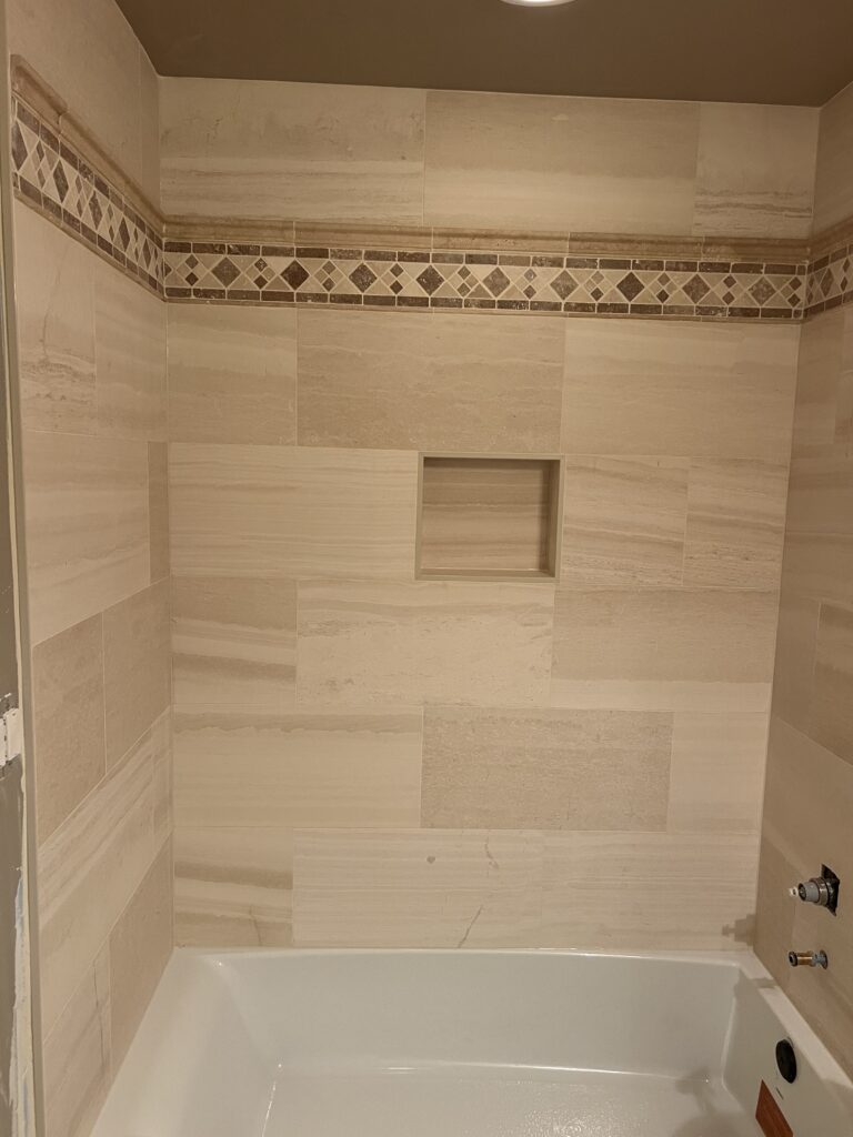 Tub surround with stone-look tile and mosaic border