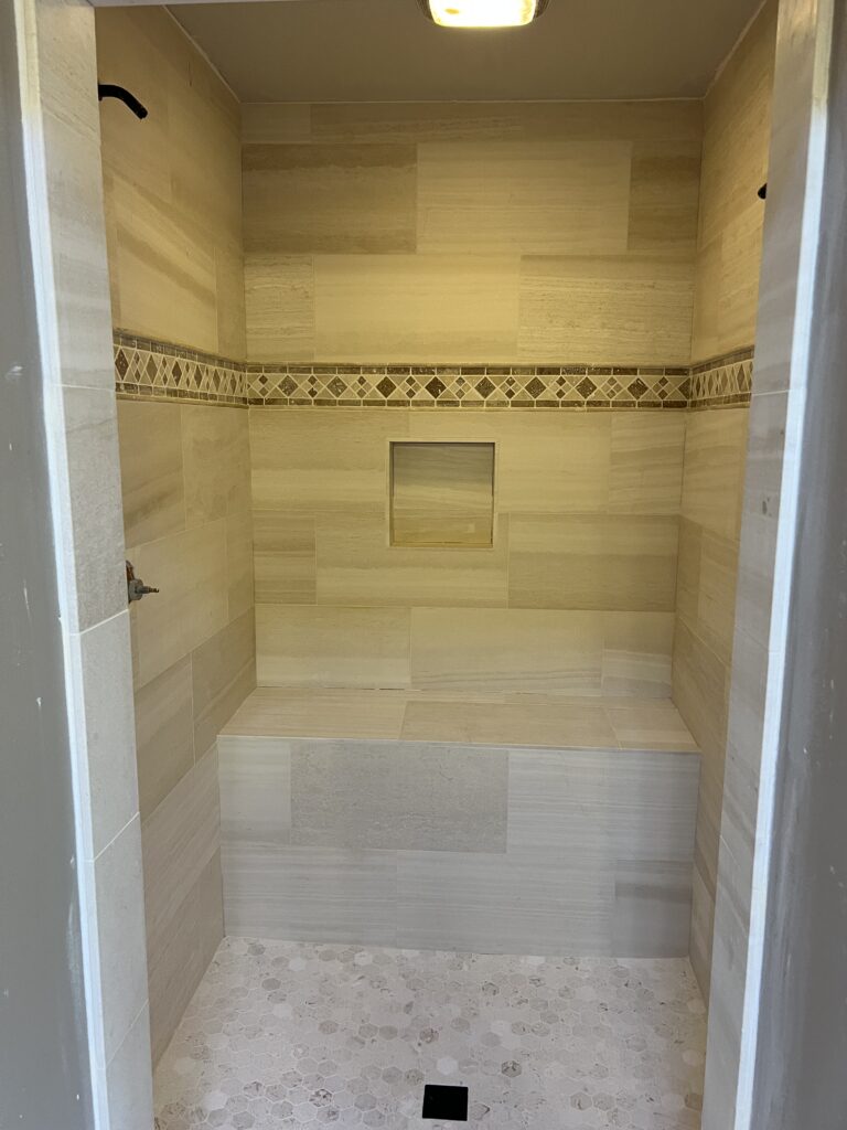 Walk-in shower with tiled bench and mosaic floor