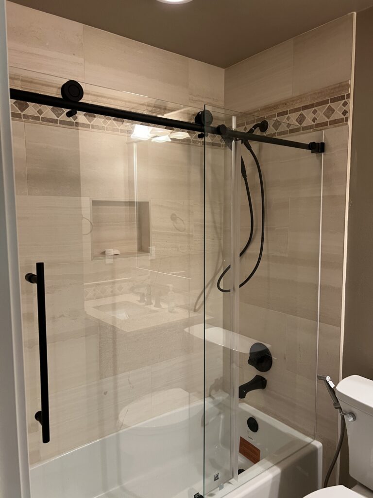 Finished tub and shower with glass door and black fixtures