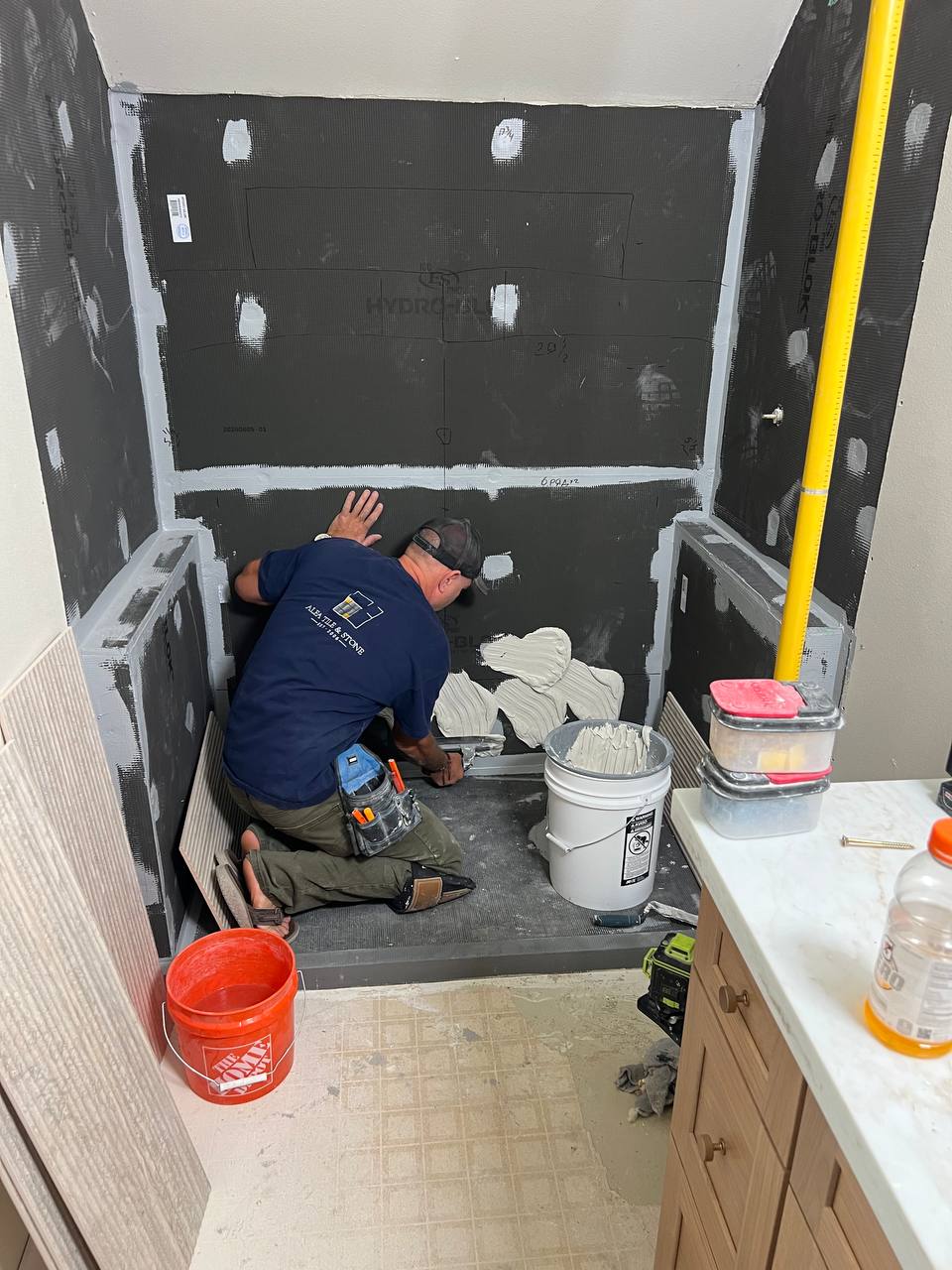 Andzhei applying thin-set to a shower wall before setting tile