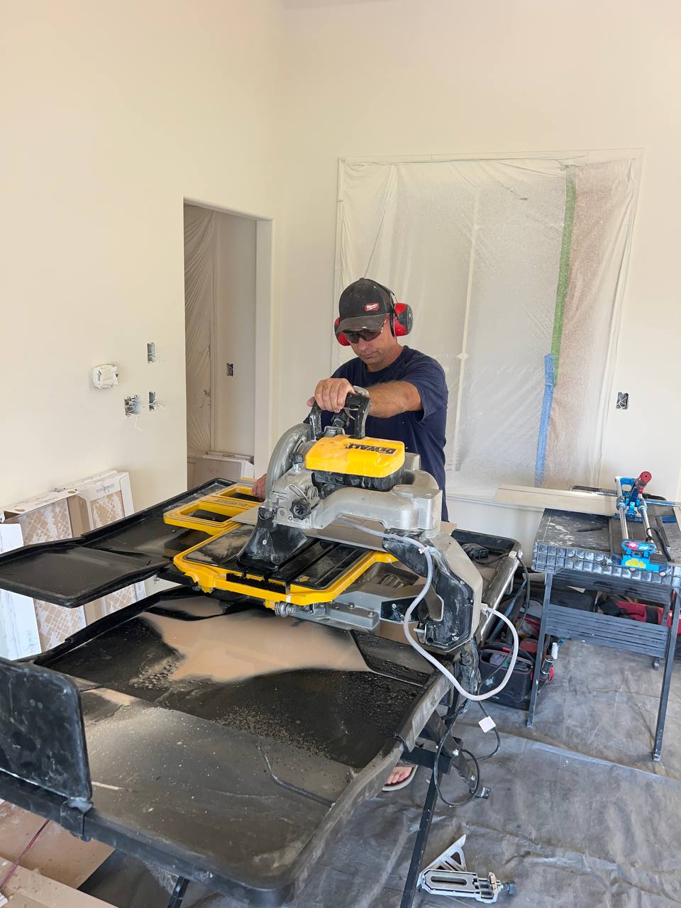 Andzhei cutting tile on a wet saw during an indoor bathroom remodel — Ability Tiles, Greater Seattle