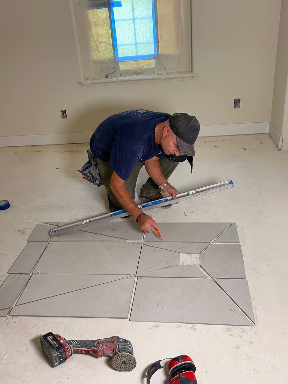 Andzhei marking a large-format floor tile layout with a level