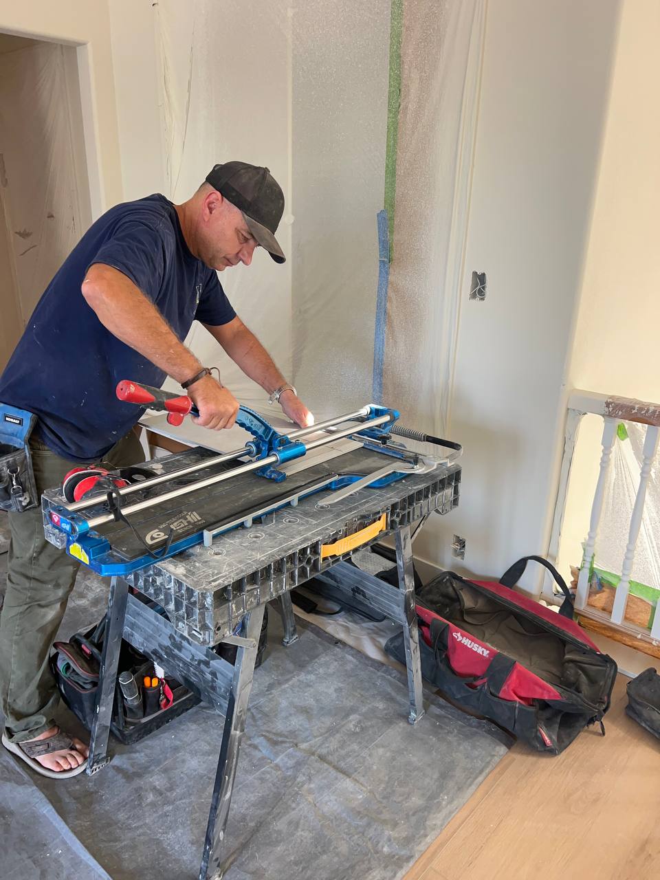 Andzhei scoring a large-format tile on a manual cutter