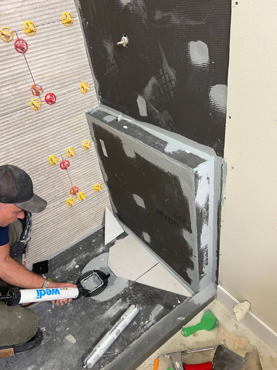 Andzhei sealing a shower drain before setting floor tile