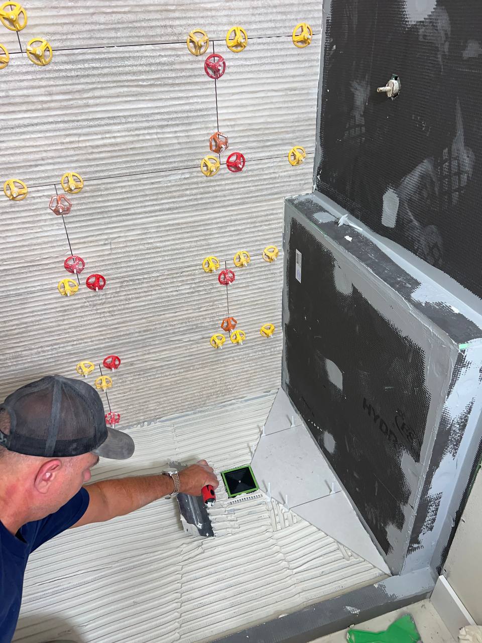 Andzhei spreading thin-set on a walk-in shower floor
