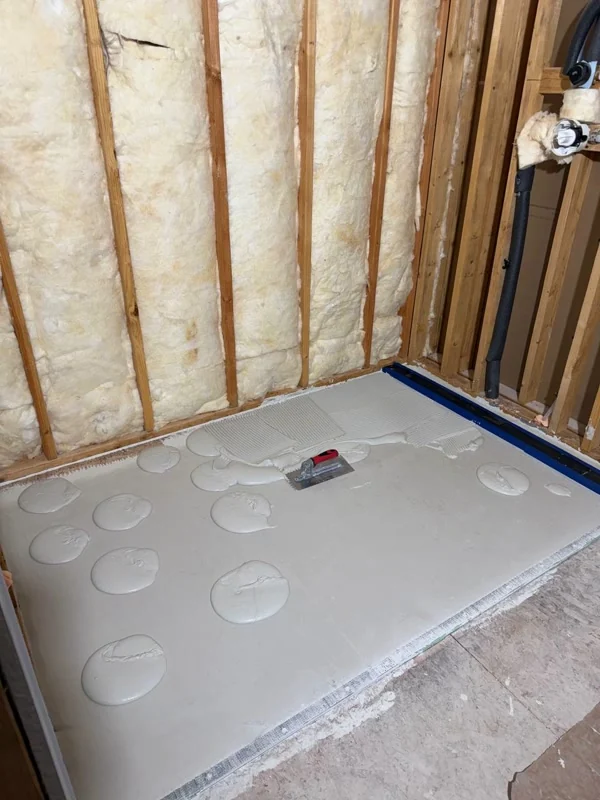 Thin-set mortar spots and trowel on shower floor before setting