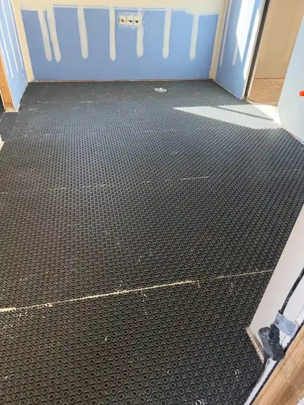 Full-room floor underlayment around a drain opening, ready for tile